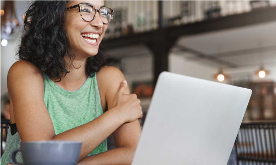 Mulher sorrindo sentada de frente para o computador